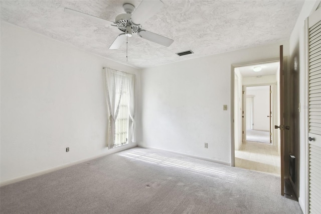 carpeted empty room featuring ceiling fan and a textured ceiling