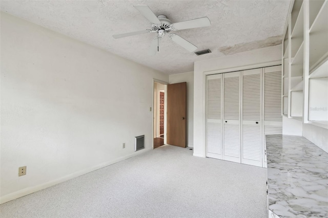 unfurnished bedroom with carpet flooring, ceiling fan, a closet, and a textured ceiling