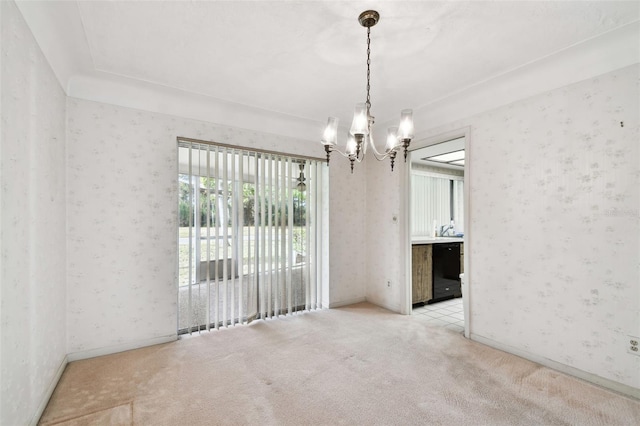 spare room featuring a chandelier and light colored carpet