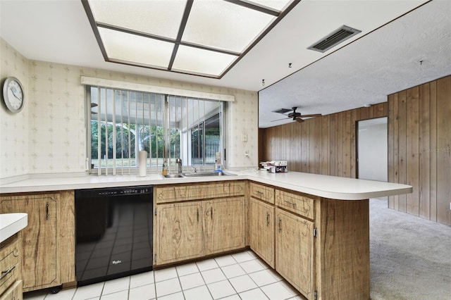 kitchen with dishwasher, wood walls, ceiling fan, light colored carpet, and kitchen peninsula