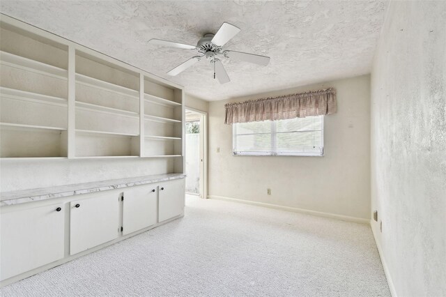 carpeted empty room featuring ceiling fan and a textured ceiling