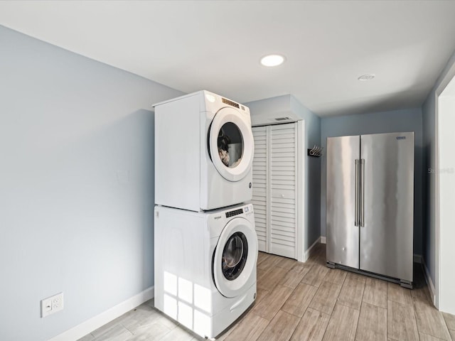 washroom with stacked washer / dryer and light wood-type flooring