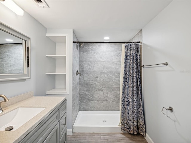 bathroom with wood-type flooring, vanity, and walk in shower