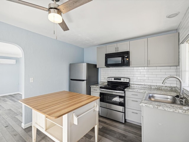 kitchen with a wall unit AC, dark hardwood / wood-style flooring, sink, and stainless steel appliances