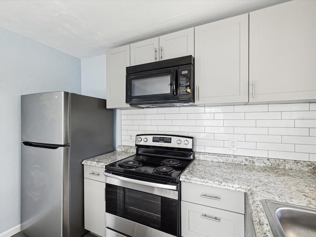 kitchen with appliances with stainless steel finishes, backsplash, white cabinetry, and light stone counters