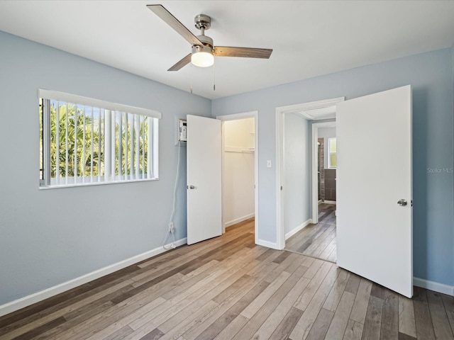 unfurnished bedroom with ceiling fan, a closet, a walk in closet, and light hardwood / wood-style flooring