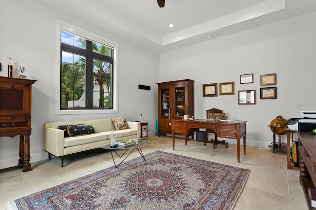 office area with light tile patterned flooring, ceiling fan, and a tray ceiling