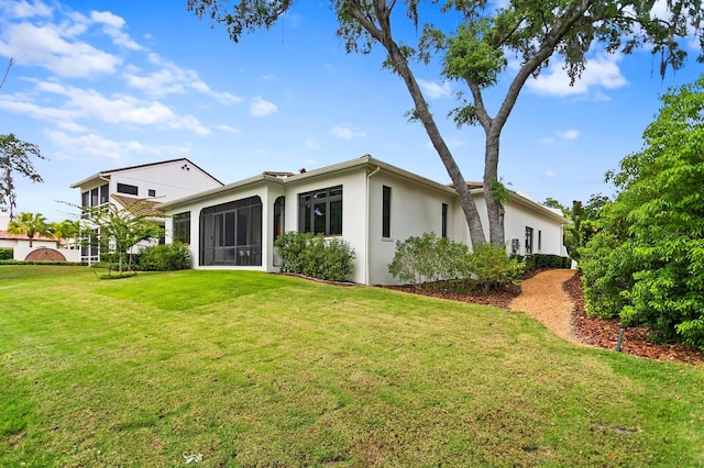 back of property featuring a lawn and a sunroom