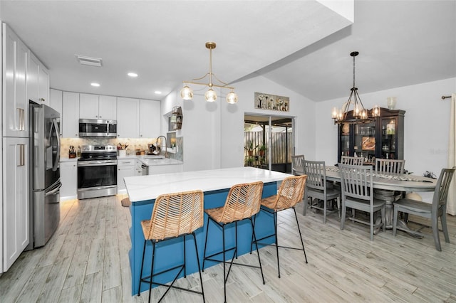 kitchen featuring stainless steel appliances, an inviting chandelier, light hardwood / wood-style floors, decorative light fixtures, and white cabinets