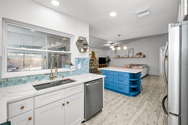 kitchen with appliances with stainless steel finishes, light stone counters, sink, light hardwood / wood-style flooring, and white cabinetry