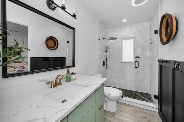 bathroom with an enclosed shower, vanity, toilet, and wood-type flooring