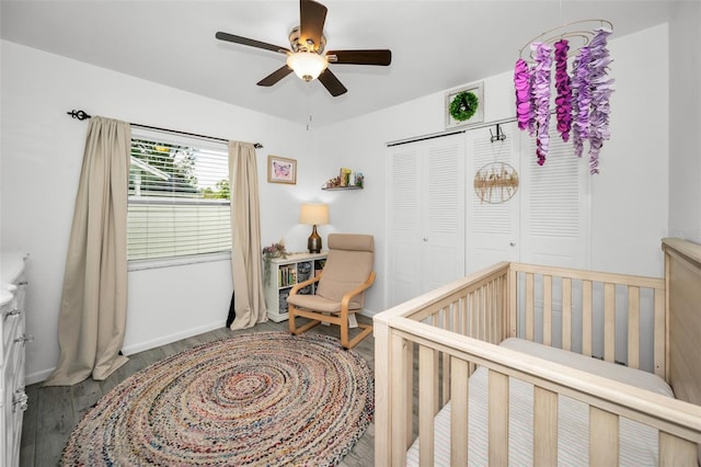 bedroom featuring a closet, ceiling fan, hardwood / wood-style floors, and a nursery area