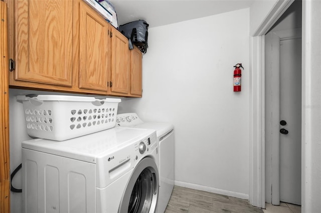 laundry area featuring cabinets, separate washer and dryer, and light wood-type flooring