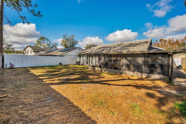 rear view of house with central AC unit and a sunroom