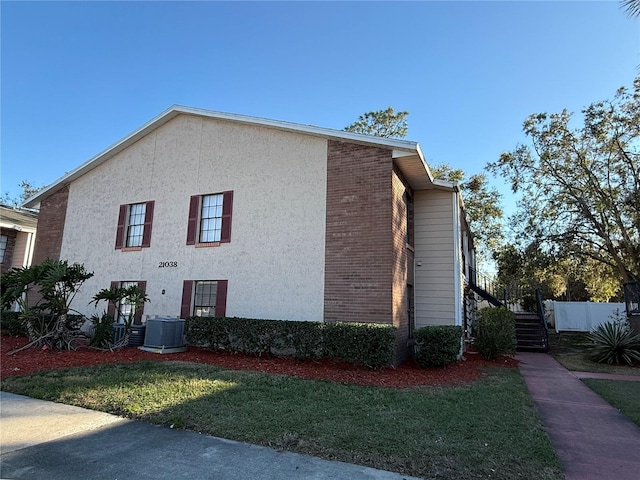 view of side of property featuring a yard and central air condition unit