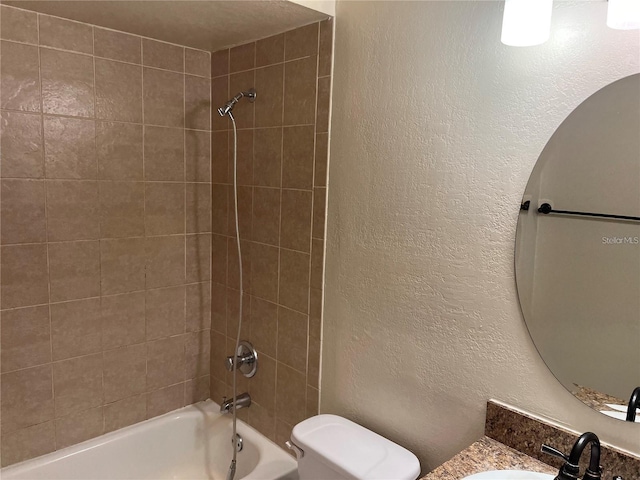 full bathroom featuring tiled shower / bath combo, toilet, and sink