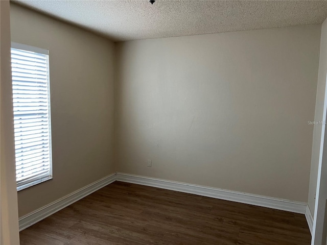 empty room featuring dark hardwood / wood-style flooring and a textured ceiling