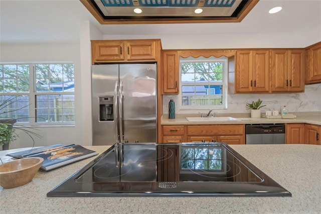 kitchen with backsplash, light stone countertops, sink, and stainless steel appliances