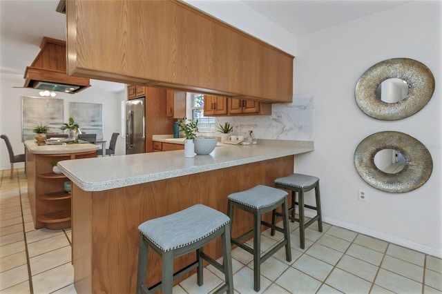 kitchen featuring kitchen peninsula, stainless steel fridge, and light tile patterned floors