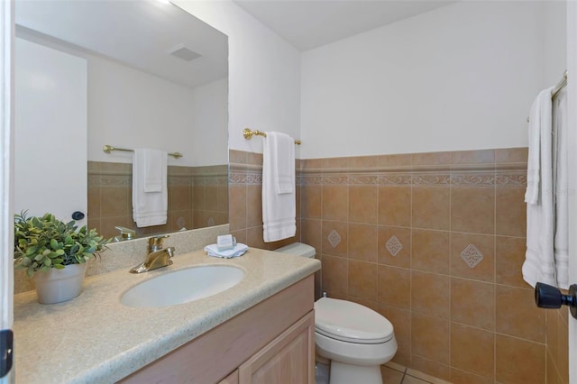 bathroom with tile patterned flooring, vanity, toilet, and tile walls