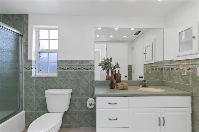 full bathroom with shower / bath combination with glass door, vanity, tile walls, and toilet