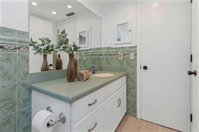 bathroom with hardwood / wood-style floors, vanity, and tile walls