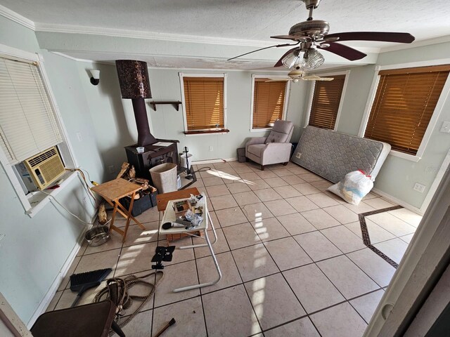 living room featuring a wood stove, cooling unit, crown molding, light tile patterned floors, and a textured ceiling