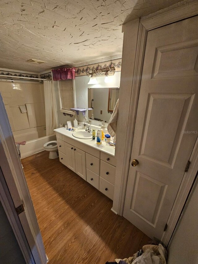 full bathroom with toilet, hardwood / wood-style floors, vanity, and shower / tub combo with curtain