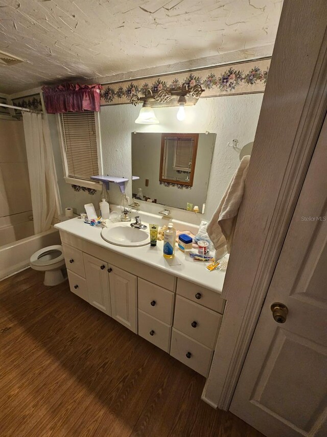 full bathroom featuring hardwood / wood-style floors, vanity, toilet, and shower / tub combo with curtain