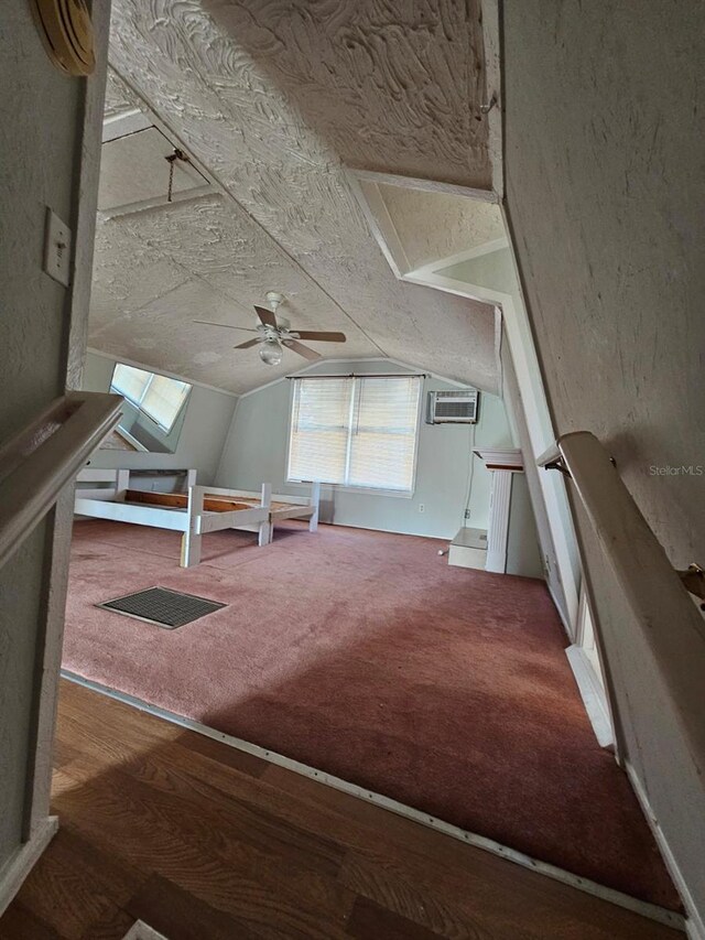 additional living space featuring a wall unit AC, ceiling fan, carpet, and vaulted ceiling