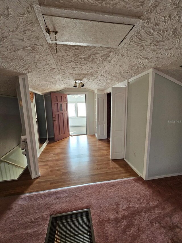 hallway featuring a textured ceiling, hardwood / wood-style flooring, and vaulted ceiling