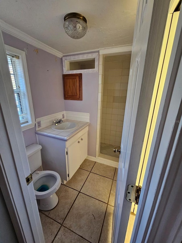 bathroom featuring tile patterned flooring, crown molding, toilet, and tiled shower