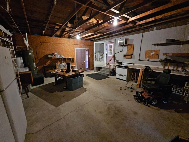 basement with white refrigerator, a wall unit AC, and a workshop area