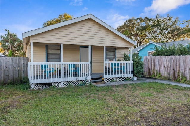 bungalow-style home with covered porch and a front yard