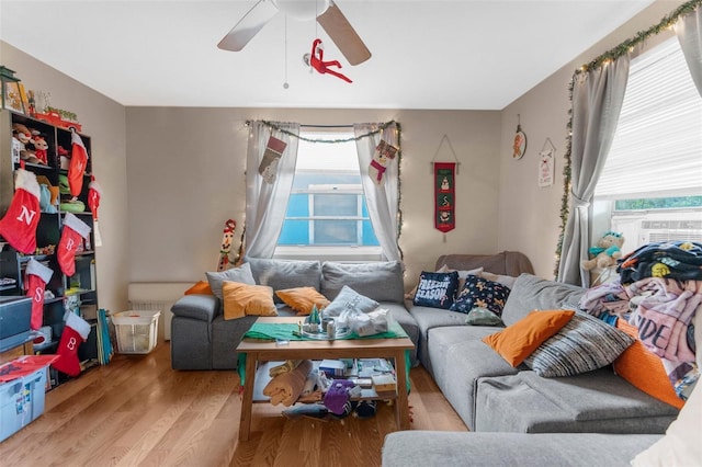 living room featuring light wood-type flooring, ceiling fan, and cooling unit