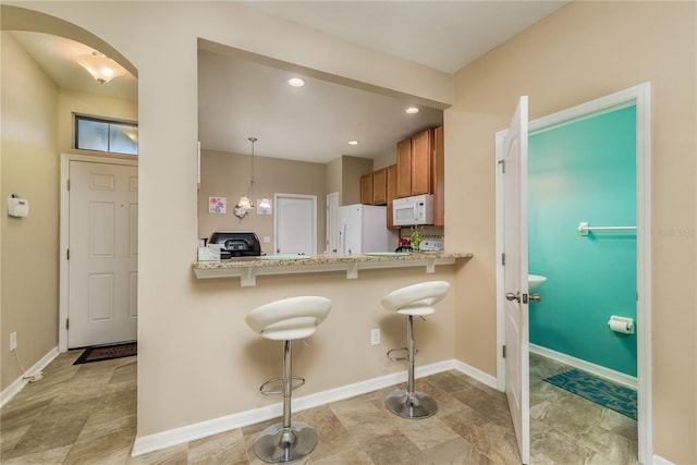 kitchen with white appliances, a kitchen breakfast bar, kitchen peninsula, a chandelier, and pendant lighting