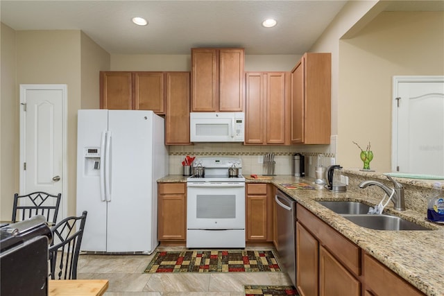 kitchen with sink, white appliances, tasteful backsplash, and light stone counters