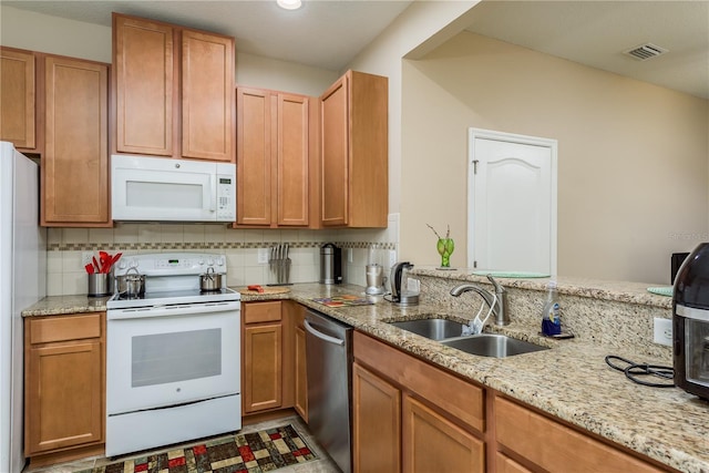 kitchen with stainless steel appliances, light stone countertops, backsplash, and sink