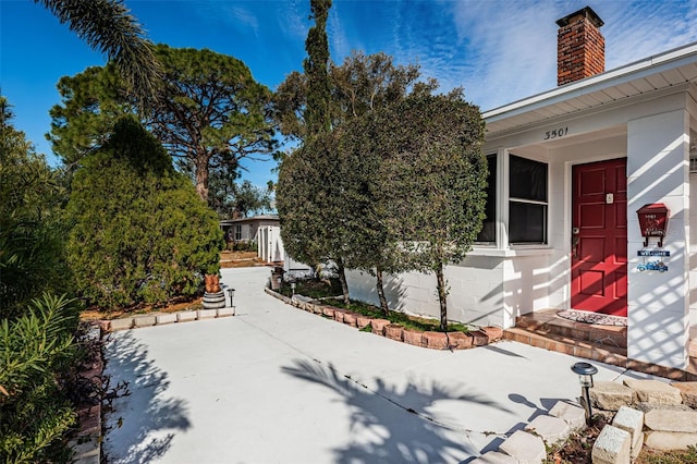 exterior space featuring a chimney, a patio area, and concrete block siding