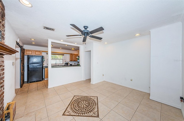 interior space with sink, ceiling fan, a barn door, light tile patterned floors, and a textured ceiling