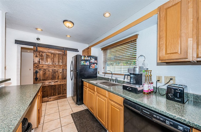 kitchen featuring a textured ceiling, sink, black appliances, a barn door, and light tile patterned flooring