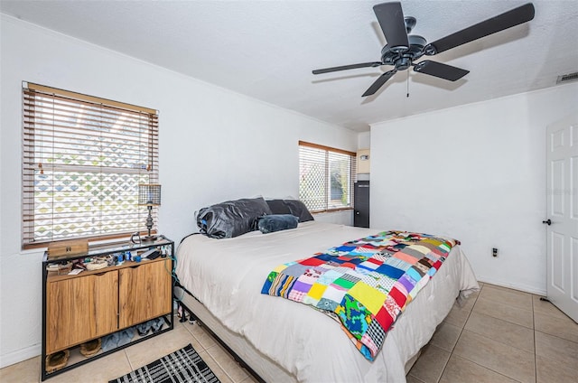 bedroom with ceiling fan, light tile patterned flooring, and a textured ceiling