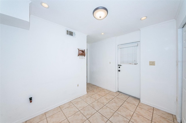 tiled empty room featuring crown molding