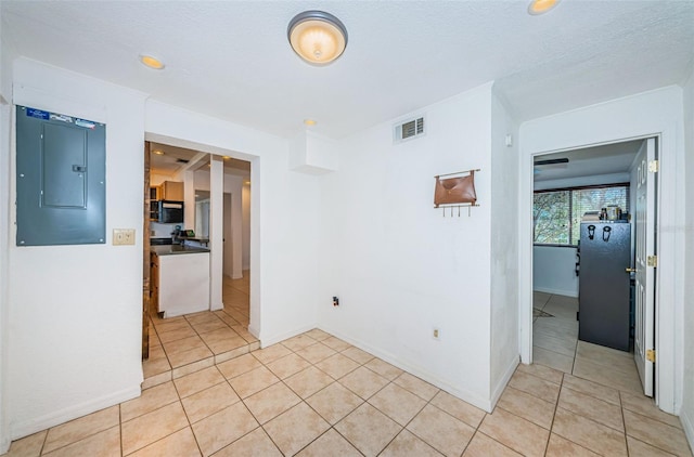 unfurnished room featuring electric panel, light tile patterned floors, and a textured ceiling