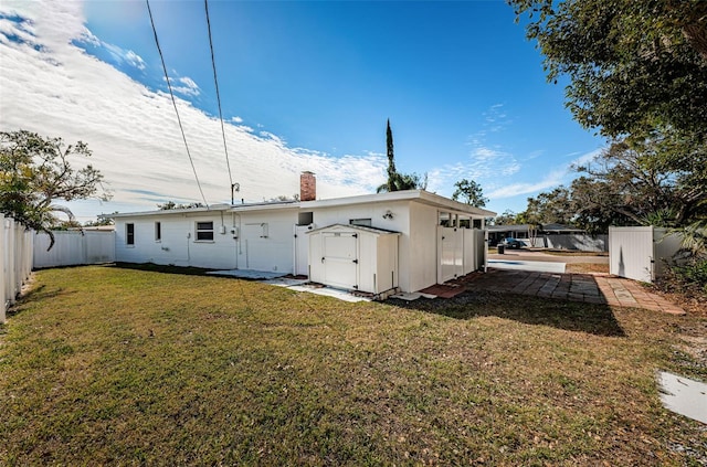 rear view of house featuring a lawn and a storage unit