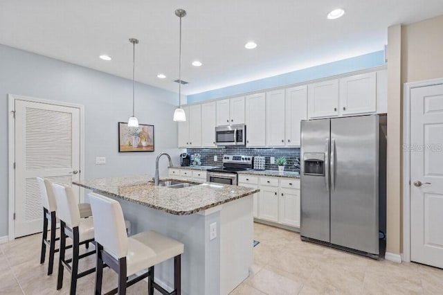 kitchen featuring white cabinetry, appliances with stainless steel finishes, an island with sink, and hanging light fixtures