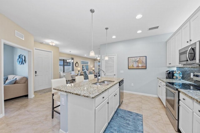 kitchen featuring sink, decorative light fixtures, appliances with stainless steel finishes, an island with sink, and white cabinets