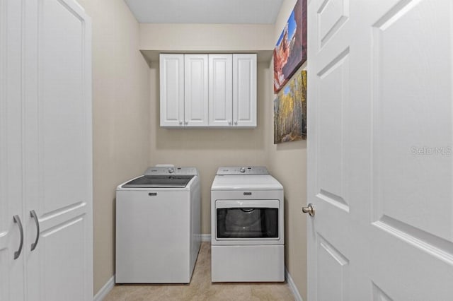 washroom featuring light tile patterned floors, washing machine and dryer, and cabinets