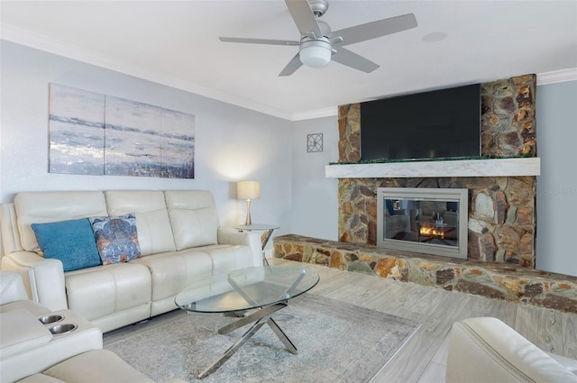 living area featuring a fireplace, crown molding, a ceiling fan, and wood finished floors