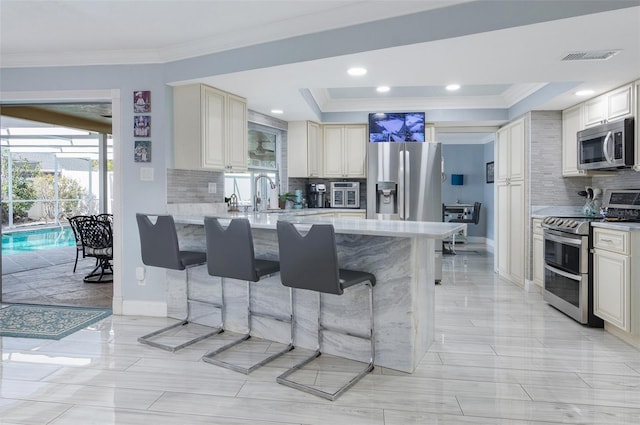 kitchen featuring ornamental molding, light countertops, a kitchen bar, and stainless steel appliances